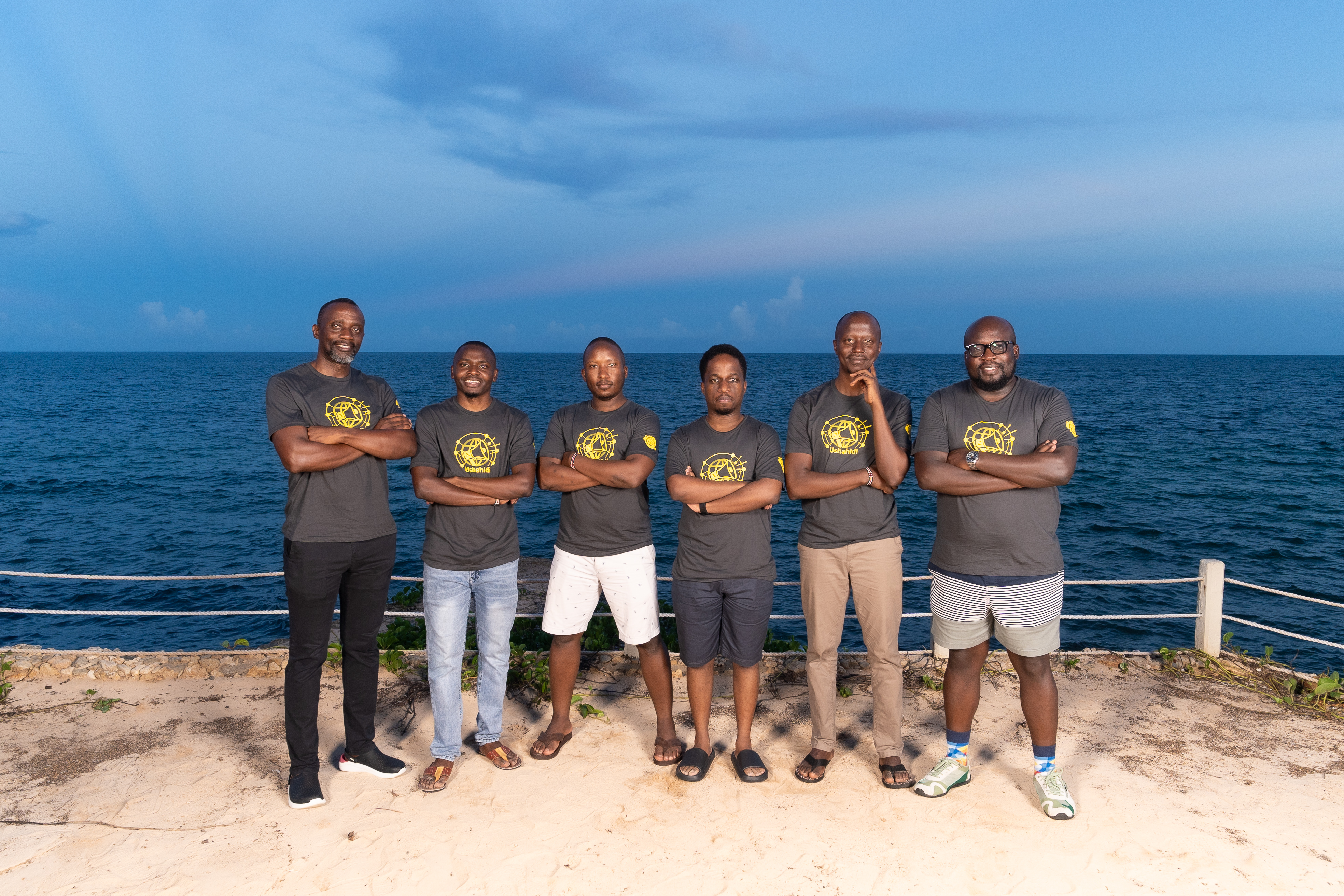 team posing for a photo on a deck by the ocean